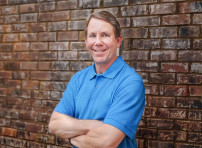 Dr. Crackel standing beside a brick wall in a professional photo